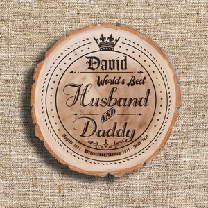 May include: A round wooden sign with a crown and the text "David World's Best Husband and Daddy" with the dates "Angela 2001, Peter 2008, Ashley 2013, Julie 2015".