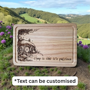 May include: A rectangular wooden cutting board with a carved illustration of a hobbit hole and the text "Chop it like it's precious". The board has a light wood grain and a recessed edge. Text can be customized.