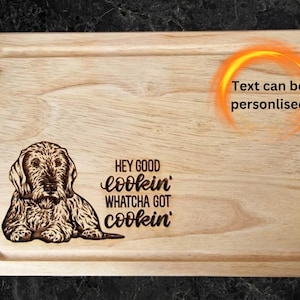 May include: A wooden cutting board with a laser-engraved image of a dog and the text "Hey good lookin' Whatcha got cookin'". The text can be personalized.