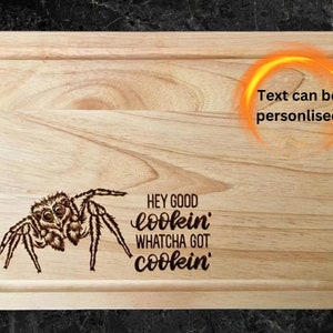 May include: A wooden cutting board with a spider design and the text "Hey good lookin' Whatcha got cookin'". The text can be personalized.
