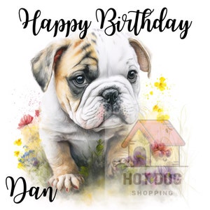 May include: Happy Birthday Dan card featuring a watercolour illustration of a bulldog puppy with brown, white and tan fur. The puppy is standing in a field of flowers with a pink doghouse in the background.
