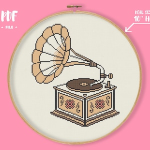Könnte beinhalten: Kreuzstichmuster eines Vintage-Grammofons in den Farben Beige, Braun und Creme. Das Design wird in einem 25,4 cm-Reifen dargestellt, mit dem Text "PDF FILE" oben. Das Grammophon ist detailliert mit einem Trichter, Plattenteller und dekorativem Schrank.