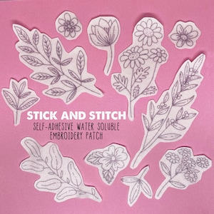 Könnte beinhalten: Ein Set mit neun weißen wasserlöslichen Stickpatches mit floralen Designs. Die Patches sind mit "Stick and Stitch, Self-Adhesive Water Soluble Embroidery Patch" beschriftet.