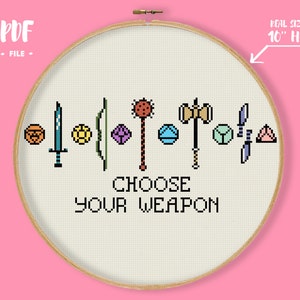 Può includere: Ricamo a punto croce con varie armi pixelate e forme geometriche. Il testo "CHOOSE YOUR WEAPON" è ricamato sotto le armi. Il cerchio misura circa 25 cm di diametro, su sfondo rosa chiaro.