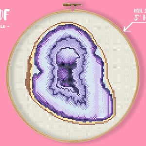 May include: Cross-stitch pattern of a geode in shades of purple, lavender, and white, set in an 8-inch embroidery hoop. The design features a detailed pixelated texture, with the text "PDF FILE" at the top.