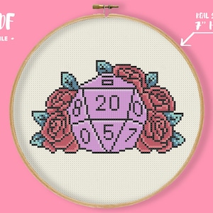 Può includere: Design a punto croce con un dado D20 con i numeri 0, 5, 7, 8, 0 e 20, circondato da rose rosa e foglie blu. Il design è in un telaio da 17,78 cm. Il testo nell'immagine recita "PDF FILE".