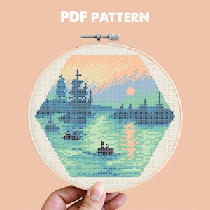 Op de afbeelding: Een kruissteeklandschap in een borduurring. Het ontwerp toont een zonsondergang boven water met bomen en boten. De tekst "PDF PATTERN" is zichtbaar bovenaan.