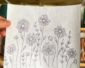 May include: A white fabric with a design of purple flowers and stems. The flowers are simple and have a daisy-like shape.