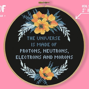 May include: A cross-stitch embroidery hoop with a black background. The text reads "THE UNIVERSE IS MADE OF PROTONS, NEUTRONS, ELECTRONS AND MORONS." Floral accents in yellow and blue surround the text. The hoop is 8 inches in diameter.