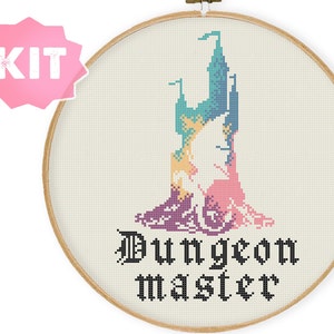 Op de afbeelding: Een kruissteekset met een regenboogkleurig kasteel met de tekst "Dungeon Master" in zwart.