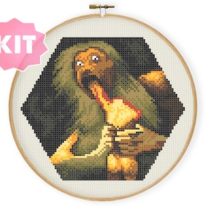 Pode incluir: Kit de ponto cruz com uma imagem pixelizada de uma criatura com cabelo verde e um objeto amarelo na boca. A imagem está dentro de uma forma hexagonal e emoldurada por um bastidor de bordado de madeira. Uma etiqueta rosa com a palavra "KIT" está no canto superior esquerdo.