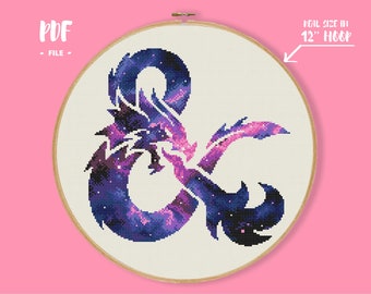May include: A cross-stitch pattern in a 12-inch wooden hoop featuring an ampersand symbol shaped like a dragon. The design uses a galaxy-inspired color palette of deep blues, purples, and pinks with white speckles. Text reads PDF FILE and REAL SIZE IN 12" HOOP.