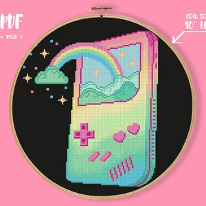 May include: Cross-stitch design featuring a pixelated handheld game console with a rainbow, clouds, and stars. The design is set against a black background within a 10-inch embroidery hoop. Text includes "PDF FILE".