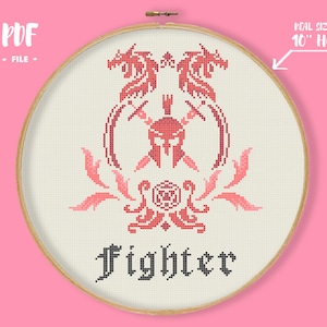 May include: A cross-stitch design in a wooden hoop, featuring a red and pink warrior emblem with a helmet, swords, and dragon-like figures. The word "fighter" is stitched below. The text "Real size in 10" hoop" is visible.