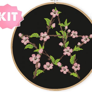 May include: A cross-stitch embroidery kit featuring a pentagram design with pink flowers and green leaves on a black background.