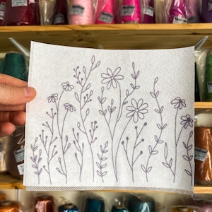 May include: A white fabric panel with a gray floral design. The design features a variety of flowers and leaves, all outlined in gray. The fabric is smooth and has a subtle texture.