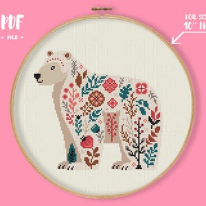 May include: A cross-stitch pattern of a polar bear, filled with floral designs in red, teal, brown, and white. The design is set in a 10-inch embroidery hoop, with the text "PDF FILE" at the top.
