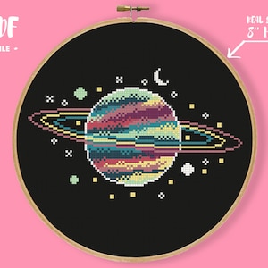 May include: A cross-stitch design featuring a planet with rings in various colours, set against a black backdrop. The design is framed in a 20 cm embroidery hoop. The text "PDF FILE" is at the top left.