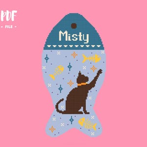 May include: A fish-shaped cross-stitch pattern featuring a light blue background with a dark brown cat wearing an orange collar. The design includes yellow fish skeletons, small blue and orange stars, and the text Misty in white at the top.