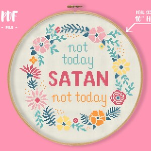 Pode incluir: Arte em ponto cruz com a frase "not today SATAN not today" em rosa, azul-turquesa e laranja. O texto é rodeado por uma grinalda floral em rosa, amarelo e azul. O diâmetro do bastidor é de 25,4 cm.