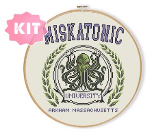 Puede incluir: Un kit de punto de cruz con el logotipo de la Universidad Miskatonic. El logotipo es un Cthulhu verde y negro con el texto "Miskatonic University" y "Arkham Massachusetts" en morado.