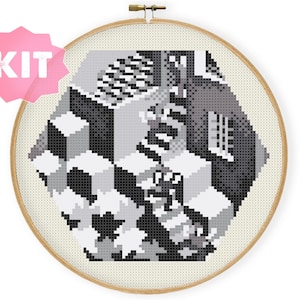 May include: Cross-stitch kit featuring an Escher-inspired geometric design in grayscale. The artwork is displayed in a wooden embroidery hoop, with a pink starburst-shaped sticker that reads "KIT".
