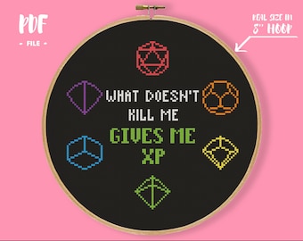 Op de afbeelding: Kruissteekborduurwerk in een borduurring met de tekst "WHAT DOESN'T KILL ME GIVES ME XP" en geometrische vormen in rood, paars, oranje, blauw en groen op een zwarte achtergrond. De ring is 20 cm in diameter. De woorden "PDF FILE" zijn ook aanwezig.