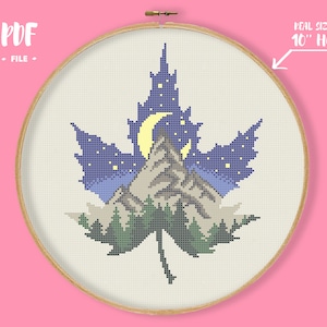 Puede incluir: Patrón de punto de cruz de un paisaje de montaña dentro de una hoja de arce azul con una luna creciente y estrellas. El patrón está diseñado para caber en un aro de 25 cm. Archivo PDF.