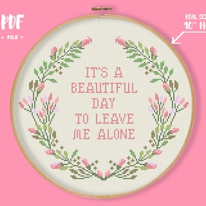 May include: A cross-stitch pattern featuring a floral wreath with the text "It's a beautiful day to leave me alone" in a 10-inch hoop.