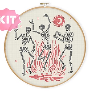 Puede incluir: Patrón de punto de cruz con tres esqueletos bailando alrededor de un fuego rojo y negro. Los esqueletos son en blanco y negro, y el fondo es blanco con acentos rojos y negros. El patrón incluye un sol y una luna en la esquina superior derecha.