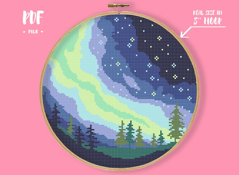 May include: A cross-stitch pattern of a night sky with a green and blue aurora borealis, a dark forest silhouette, and a scattering of white stars. The pattern is displayed in an 8-inch embroidery hoop.