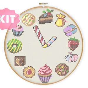 Può includere: Un kit di ricamo a punto croce con un quadrante di orologio con vari dolciumi, tra cui cupcake, ciambelle, bastoncini di zucchero e biscotti. Le lancette dell'orologio hanno la forma di un bastoncino di zucchero.