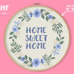 Könnte beinhalten: Ein Kreuzstich-Stickrahmen mit den Worten "HOME SWEET HOME" in Blau, umgeben von einem floralen Kranz aus blauen Blumen und grünen Blättern. Der Rahmen hat einen Durchmesser von ca. 30 cm. Der Text "PDF - FILE" befindet sich oben links.