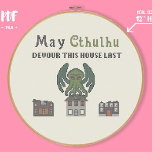 Puede incluir: Arte de aro de punto de cruz con el texto "May Cthulhu Devour This House Last". El diseño presenta una figura verde de Cthulhu sobre tres casas pixeladas. El aro mide unos 30 cm de diámetro.