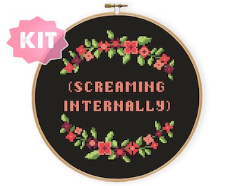 May include: A black embroidery hoop with a floral wreath design and the text "(SCREAMING INTERNALLY)" in pink.