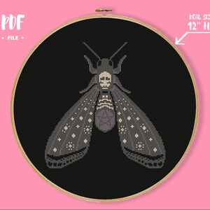 May include: A black and white cross stitch pattern of a moth with a skull on its head and a pentagram on its body. The pattern is designed to fit in a 12 inch hoop.