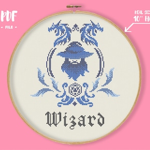 May include: Cross-stitch pattern featuring a blue wizard design within a wooden embroidery hoop. The design includes a wizard figure, dragons, and the word "Wizard" in a gothic font. The hoop is approximately 10 inches in diameter.