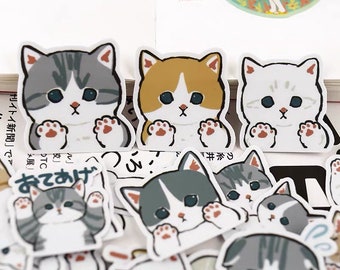May include: A sheet of stickers featuring adorable cartoon cats with different expressions. The cats are in various poses, including sitting, standing, and waving. The stickers are printed on white paper with a glossy finish.