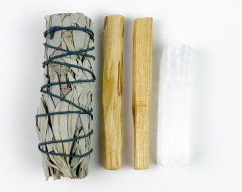 Può includere: Un set di quattro strumenti per la purificazione, tra cui un fascio di salvia bianca, due bastoncini di legno e un cristallo di selenite bianco.
