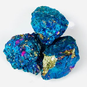 May include: Three iridescent blue, green, and gold pyrite stones. The stones have a rough, natural texture.
