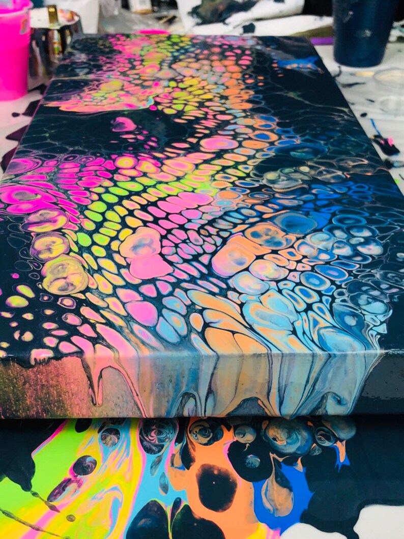 Puede incluir: Pintura abstracta sobre lienzo con fondo negro y remolinos coloridos de rosa, azul, verde y amarillo.