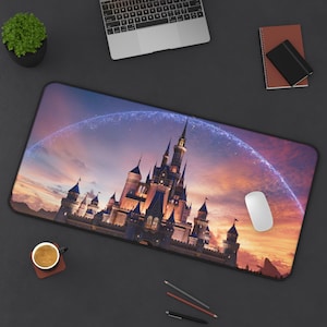 May include: A rectangular mouse pad featuring a detailed illustration of a fairytale castle under a sunset sky. The castle has multiple towers and spires, with a glowing arch above. A white mouse and other office supplies are also visible.