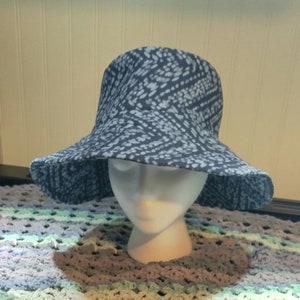 May include: A blue and white patterned sun hat with a wide brim. The hat is sitting on a crocheted surface.