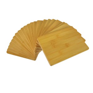 May include: A collection of rectangular bamboo cutting boards, arranged in a fan-like pattern. The boards are a light, natural wood color, with visible grain patterns. The boards are approximately 8 inches long and 6 inches wide.