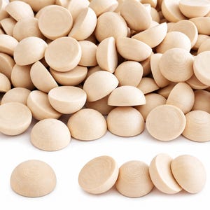 May include: A large collection of unfinished light-colored wooden half-spheres. Each piece features a smooth, rounded top surface and a flat base, showcasing the natural grain patterns of the wood in a uniform, circular shape throughout the pile.
