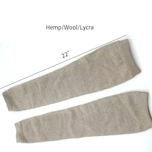 Könnte beinhalten: Zwei beige Armstulpen, jeweils etwa 56 cm lang, aus einer Mischung aus Hanf, Wolle und Lycra. Der Text "Hemp/Wool/Lycra" steht über den Armstulpen. Der Text "22" steht über den Armstulpen.