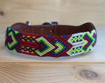 May include: A colorful dog collar with a geometric pattern in shades of red, green, blue, and white. The collar is made of leather and has a metal buckle.
