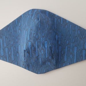 May include: Blue face mask with a pattern of black spoons on it.