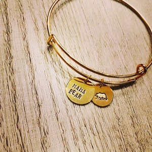May include: Gold charm bracelet with two charms. The first charm says "Mama Bear" and the second charm is a bear silhouette.