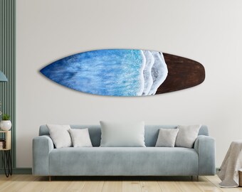Op de afbeelding: Een blauw en bruin surfboard met een wit golfontwerp. Het surfboard hangt aan een witte muur in een woonkamer.